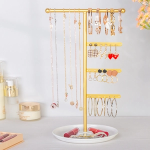 Detailed view of the golden metal multi-tier earring rack with white ceramic storage tray