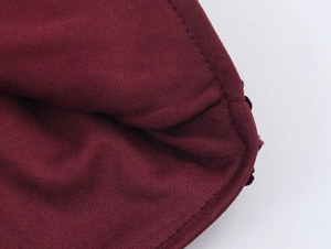 Detailed macro view of dark red knitted cotton fabric texture and sewing stitches