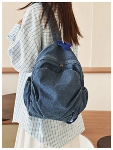 Detail of vintage navy blue denim backpack showing textured fabric and side pockets