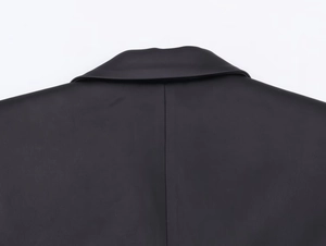 Close-up of black herringbone wool blazer showing woven texture and collar details