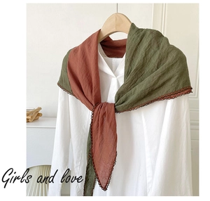 Detail of two-tone brown and green linen shawl with crochet lace edge on a white shirt