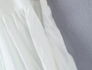 Detail view of white bubble top featuring a side invisible zipper and waist pleating technique