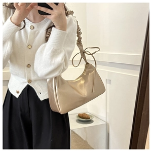 Detail der champagner-goldenen Hobo-Tasche mit Scrunchie-Riemen und zarter Schleife