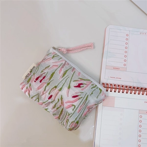 Detailed view of pink tulip embroidery on fabric coin purse with pink braided strap
