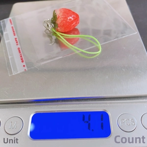 Close-up of a 4.1g realistic resin strawberry charm on a digital scale for weight display