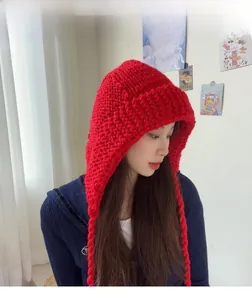 Gros plan du bonnet à capuche en grosse maille rouge avec des tresses décoratives