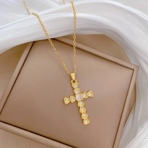 Close-up of a gold cross pendant with sparkling crystals on a luxurious white silk backdrop