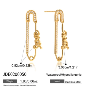 Détail de boucles d'oreilles épingle à nourrice dorées avec lettres LOVE et zircons