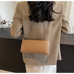Brown leather baguette bag with thin strap shown in a lifestyle shoulder carry shot