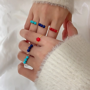 Detail of beaded rings in red, blue, and turquoise on gold and silver slim bands