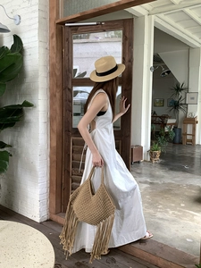 Borsa da spiaggia in paglia intrecciata a mano, vista dettaglio con lunghe frange boho.
