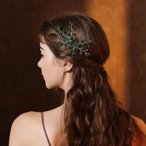 Détail d'un peigne à cheveux en cristal vert fait main dans un chignon de mariée
