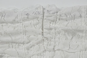 Close-up of invisible back zipper on white floral crochet lace dress with detailed texture