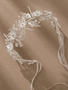 Close-up of handmade bridal headband with silver wire, crystals, pearls and white ribbons