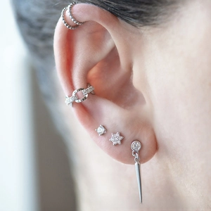 Detailed view of silver spike earrings with zircon studs and ear cuffs on model