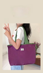 Detail view of large purple foldable oxford shopping bag with green straps on model