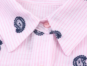 Gros plan détaillé du col brodé de motifs paisley sur une chemise à rayures roses