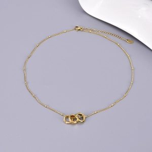 Detail of gold beaded chain with interlocking triple rings and green zircon pendant