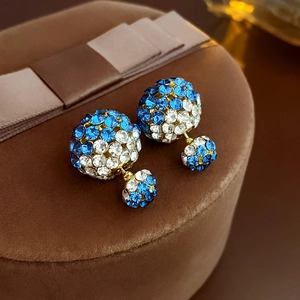 Makroansicht der blau-weißen Strass-Doppelkugel-Ohrringe auf braunem Samt