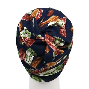 Detail of navy turban with colorful feather leaves and elegant twisted knot design