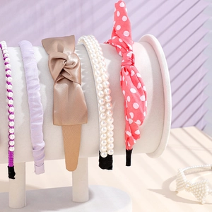 Velvet display stand showing various stylish headbands including pearls and bow knots