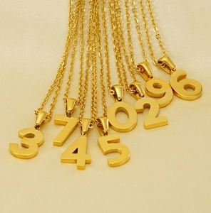 Close-up of 18K gold plated stainless steel number pendants on champagne silk fabric
