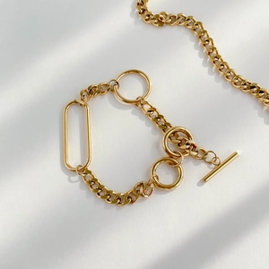 Detail of golden geometric thick chain necklace with a T-bar toggle clasp on white background