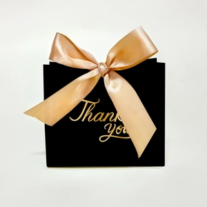 Close-up of black wedding gift box with champagne ribbon and gold Thank You lettering