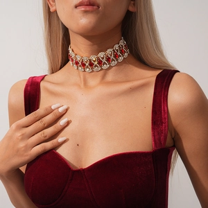Detail of vintage gold choker with red teardrop gemstones and white crystals on model