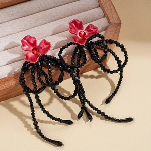Detail view of flower tassel earrings featuring red floral studs and long black bead drops