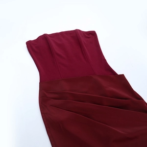 Détail d'une robe longue bordeaux avec plis élégants à la taille et mélange de tissus