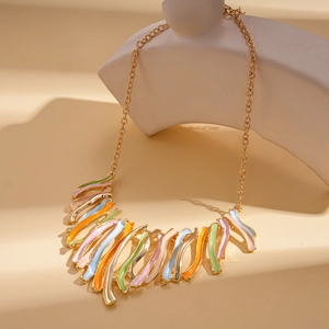 Détail de modules géométriques irréguliers en émail coloré et collier à franges dorées