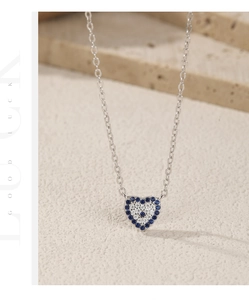 Macro shot of a heart-shaped silver necklace with pavé blue and white stones