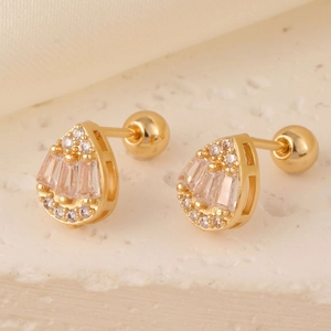 Macro shot of gold teardrop studs with baguette and round zircons and screw ball backs