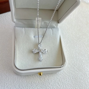 Macro detail of silver cross pendant with square zircons in a white jewelry box