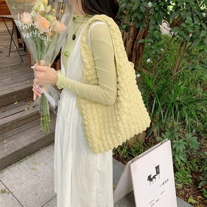 Detail of light yellow cloud bubble tote bag with quilted texture in outdoor setting