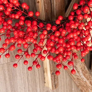 Christmas wreath with vibrant red berries and rustic brown branches on wood background