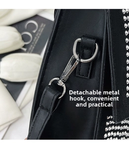 Nahaufnahme von abnehmbarem Silberhaken und D-Ring an schwarzer Tasche mit Nieten
