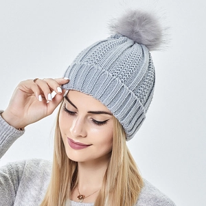 Grey chunky knit beanie featuring a fluffy pompom and fold-over cuff for winter warmth