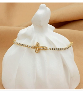 Detailed view of a gold-plated cross bracelet with micro-paved sparkling cubic zirconia