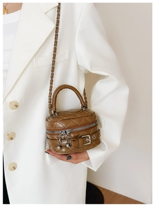 Detailed view of a brown quilted cylindrical handbag with a metal chain strap and top handle
