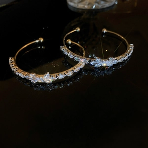 Elegant gold bow-shaped open bangle with sparkling cubic zirconia on a black surface