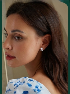 Detail shot of a silver gingerbread man earring with a pink heart stone on ear