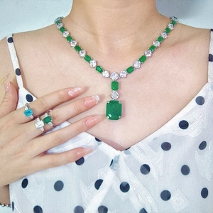 Detailed close-up of emerald green square-cut ring with side stone pave setting