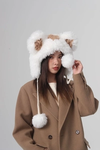 Detailed close-up of fluffy faux fur bear ears and white pom-poms on a plush winter hat