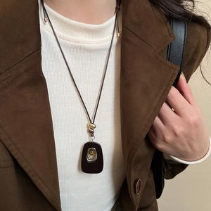 Detail of tiger eye stone oval pendant with retro brown cord on a beige sweater