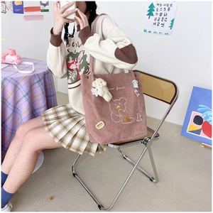 Detail of pink corduroy tote bag with cartoon bear pattern and plush bear pendant