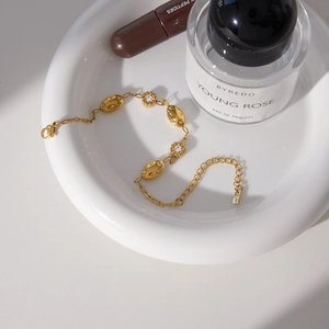 Dettaglio macro del bracciale placcato oro 18 carati con trame ovali e ciondoli a fiori