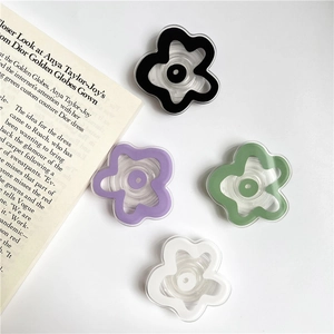 Flat lay of colorful acrylic flower phone grips in black, purple, green, and white colors