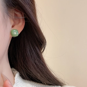 Close-up of translucent green square resin earring worn on ear with soft lighting